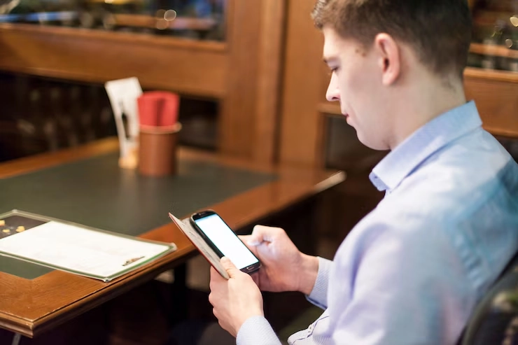 Man browsing a smartphone in a restaurant, using a mobile-friendly website.
